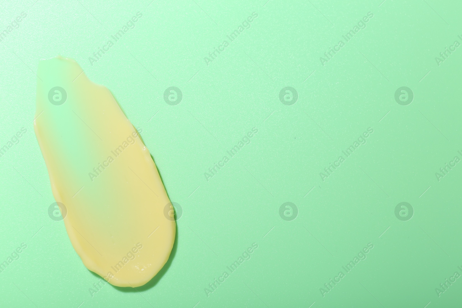 Photo of Cream sample on light green background, top view. Space for text