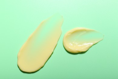 Photo of Cream samples on light green background, top view