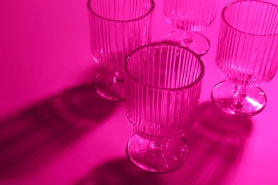 Photo of Empty glasses on pink background, closeup. Color tone effect