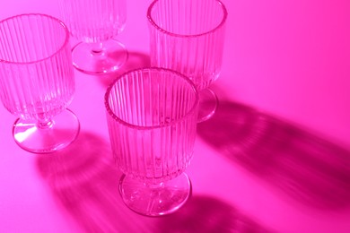 Photo of Empty glasses on pink background, closeup. Color tone effect