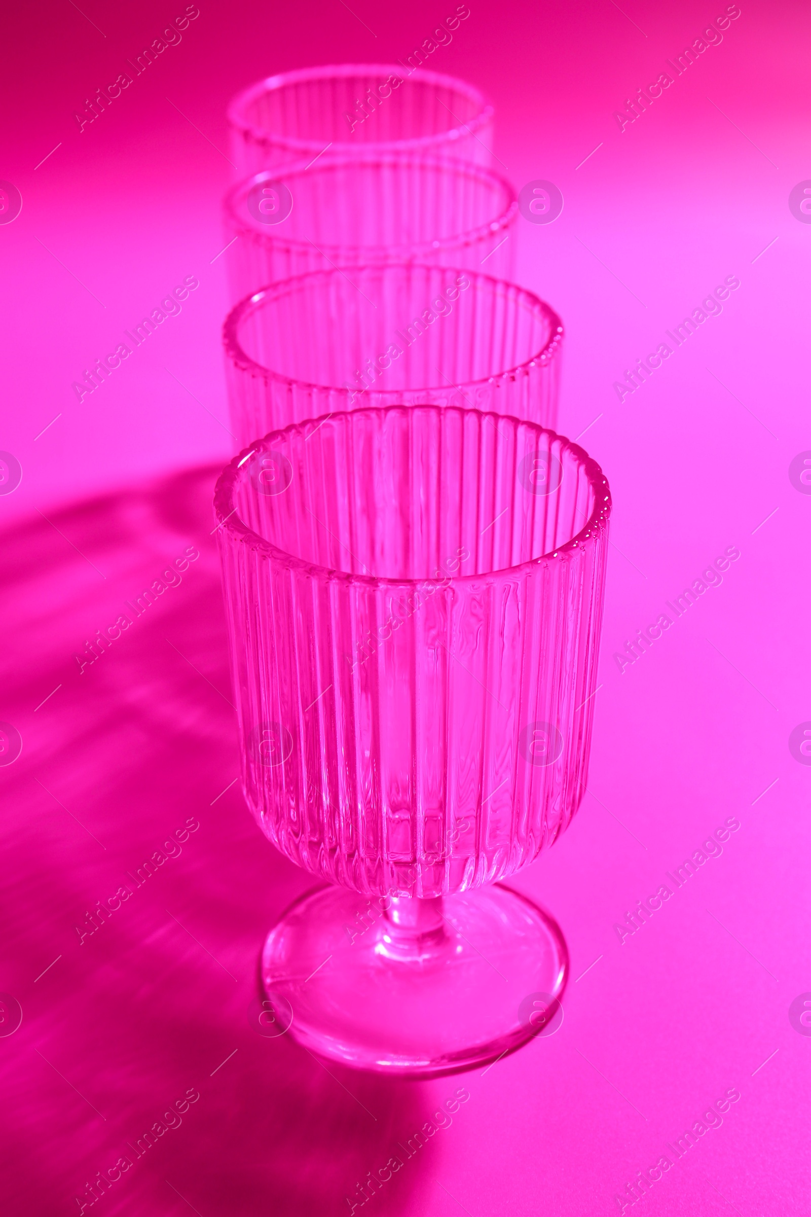 Photo of Empty glasses on pink background, closeup. Color tone effect