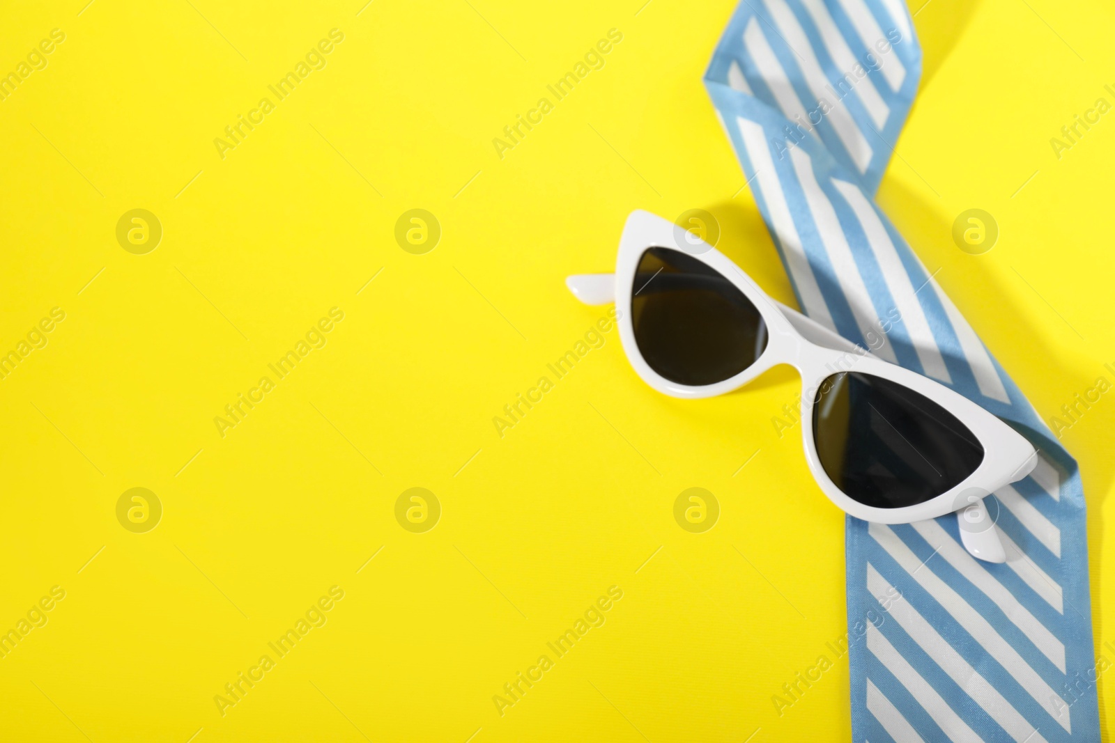 Photo of Stylish sunglasses and elegant scarf on yellow background, top view. Space for text