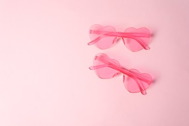 Photo of Stylish heart shaped sunglasses on pink background, top view. Space for text