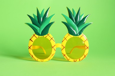 Photo of Creative pineapple shaped sunglasses on green background