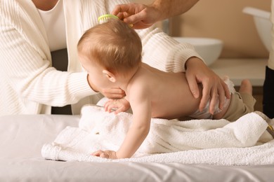 Photo of Parents brushing hair of their little baby indoors, closeup