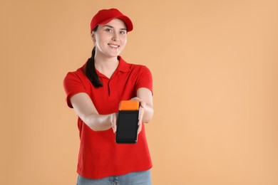 Photo of Happy courier with payment terminal on beige background, space for text