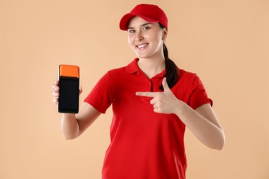 Photo of Happy courier with payment terminal on beige background