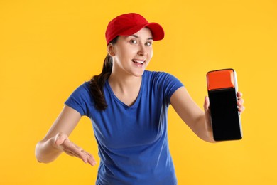 Photo of Happy courier with payment terminal on yellow background