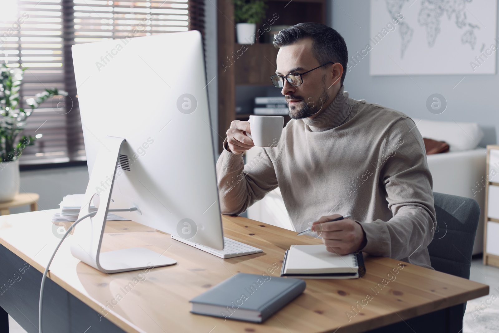 Photo of Handsome man working with computer at desk indoors. Home office