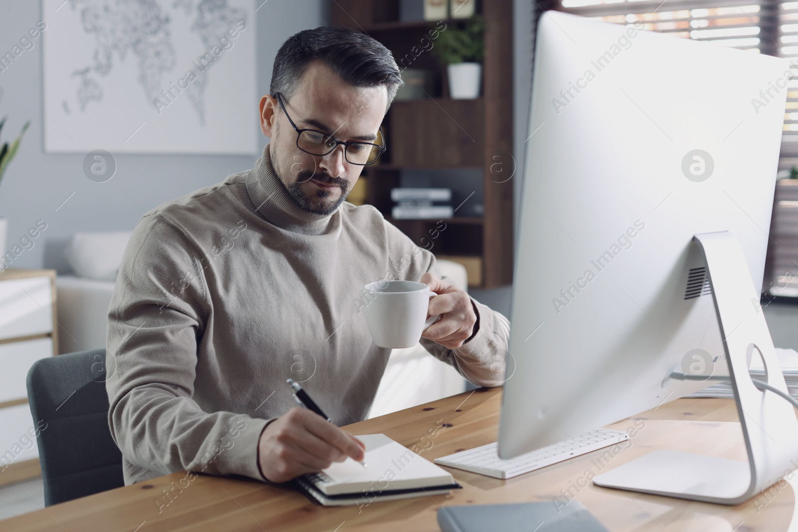 Photo of Handsome man working with computer at desk indoors. Home office