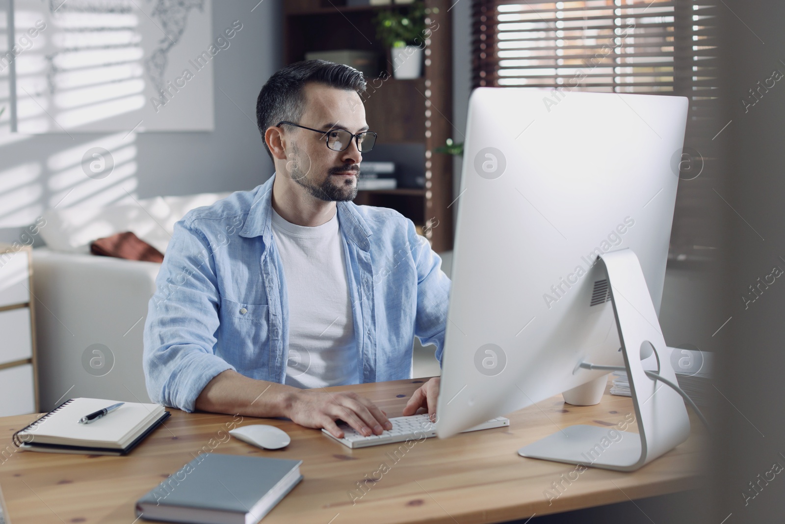 Photo of Handsome man working with computer at desk indoors. Home office