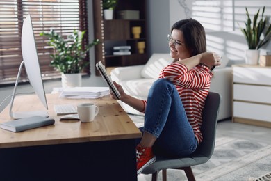 Photo of Happy woman working at desk with computer indoors. Home office