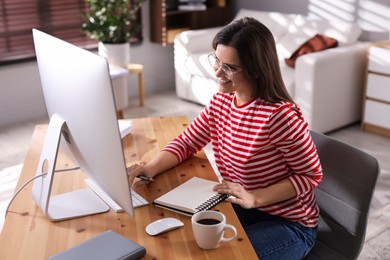 Happy woman working with computer at desk indoors. Home office