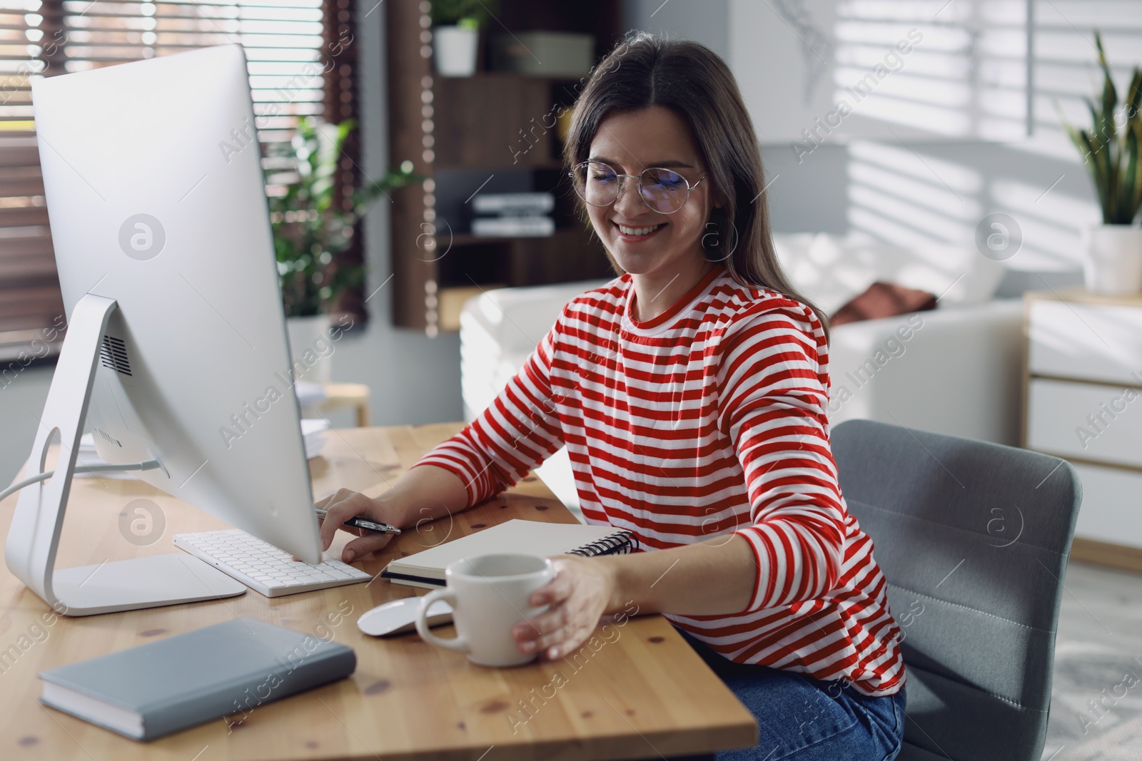 Photo of Happy woman working with computer at desk indoors. Home office