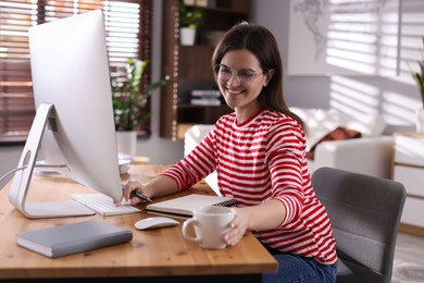 Photo of Happy woman working with computer at desk indoors. Home office