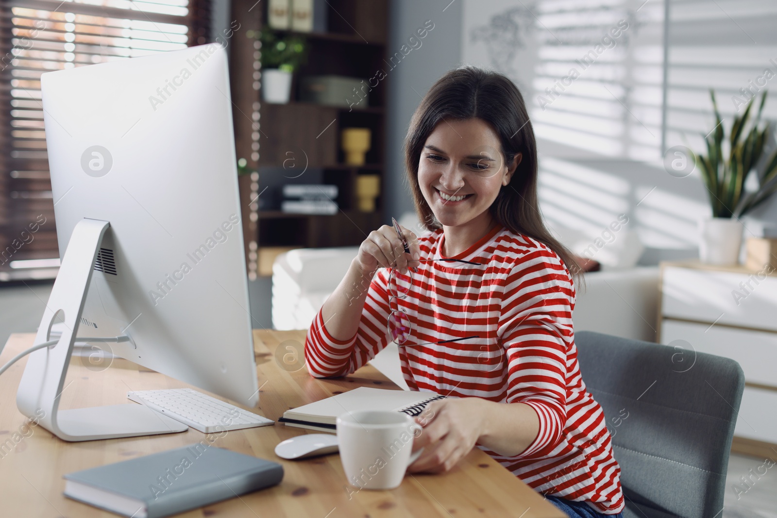 Photo of Happy woman working with computer at desk indoors. Home office