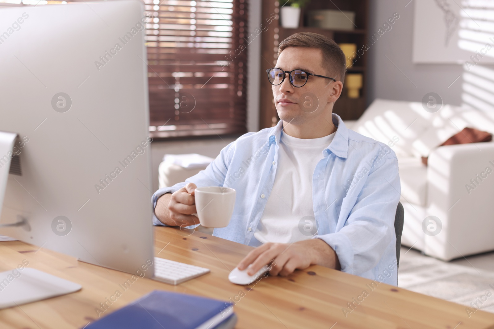 Photo of Handsome man working with computer at desk indoors. Home office