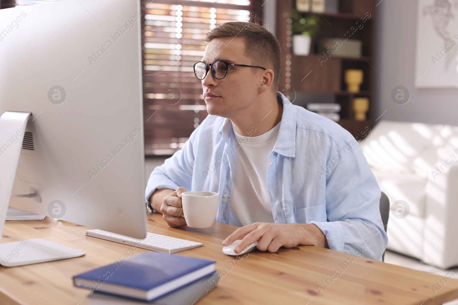 Photo of Handsome man working with computer at desk indoors. Home office