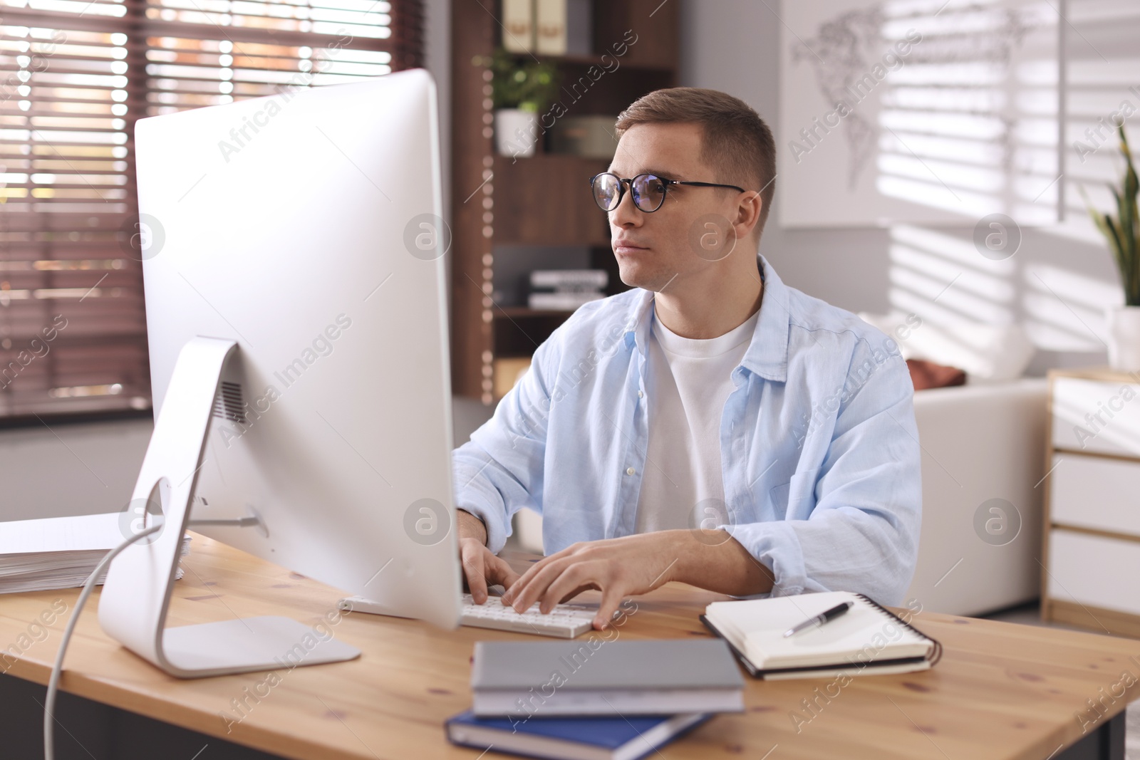 Photo of Handsome man working with computer at desk indoors. Home office