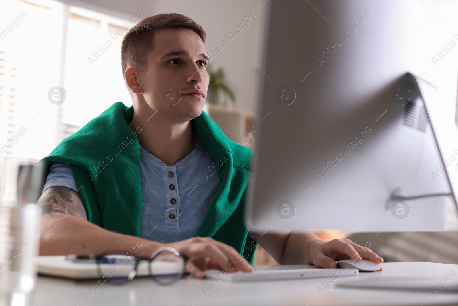 Photo of Handsome man working with computer at desk indoors. Home office