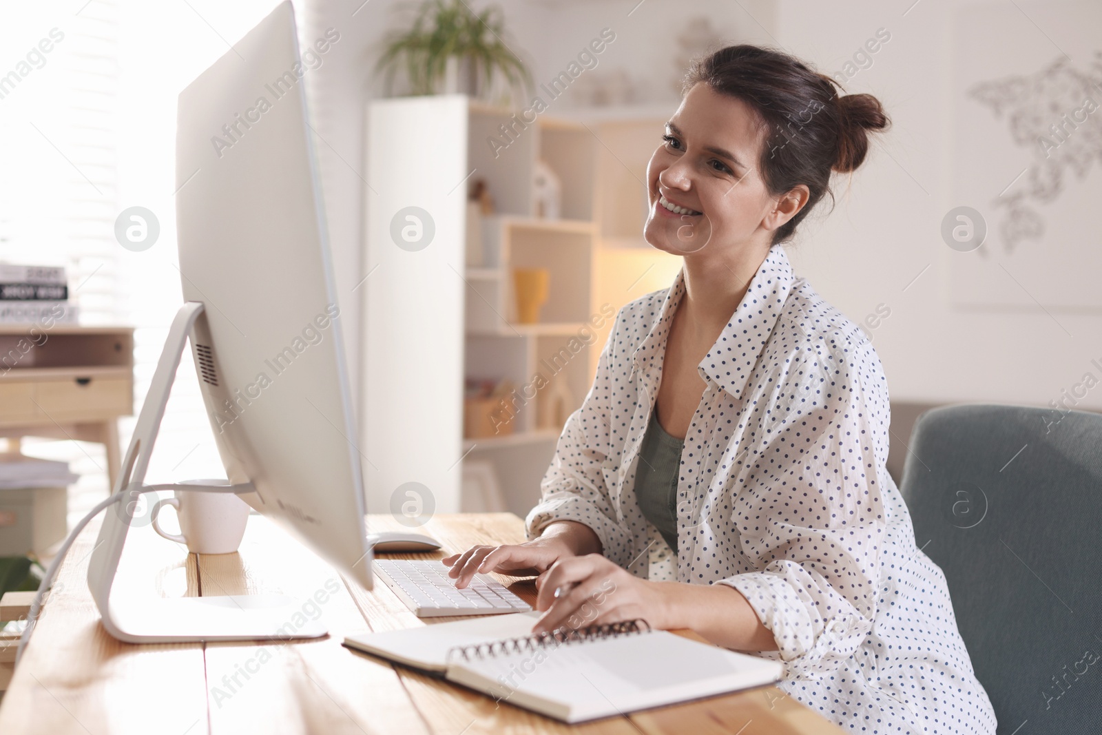 Photo of Happy woman working with computer at desk indoors. Home office