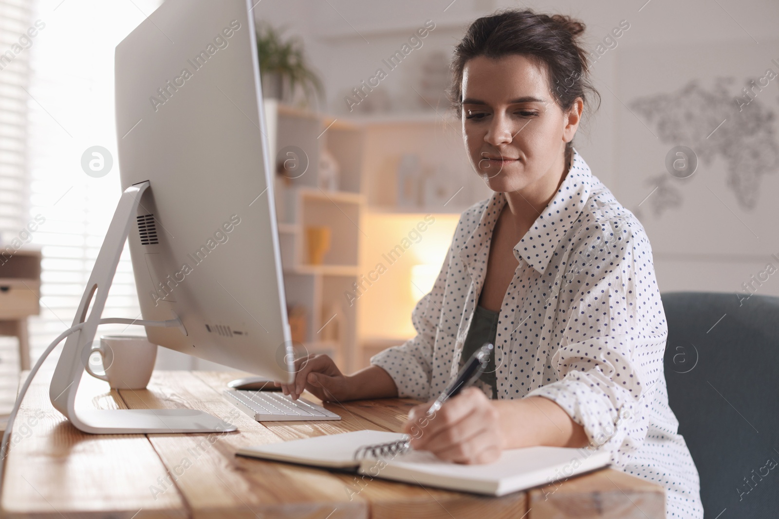 Photo of Beautiful woman working with computer at desk indoors. Home office