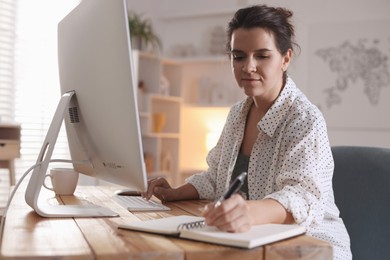 Photo of Beautiful woman working with computer at desk indoors. Home office