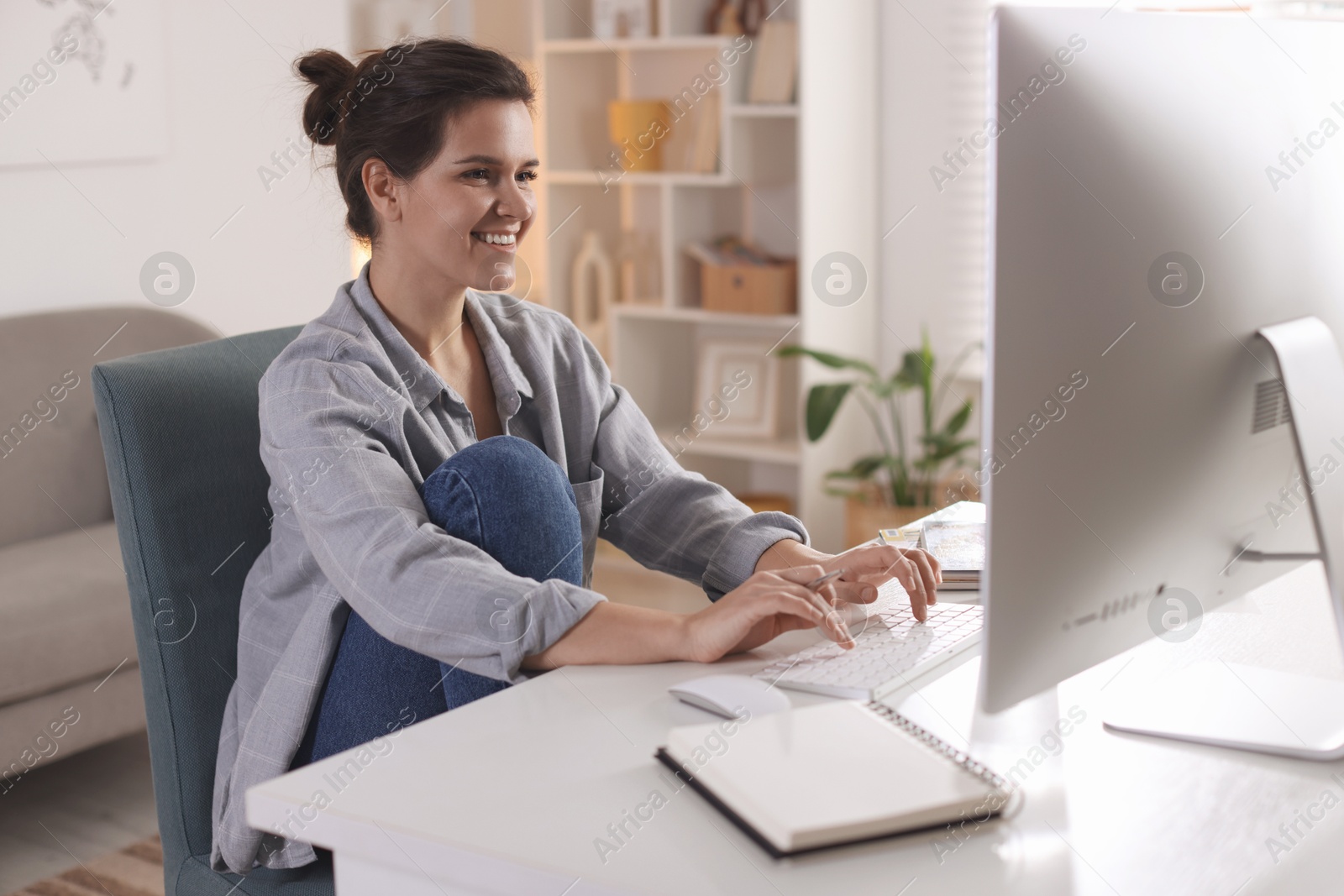 Photo of Happy woman working with computer at desk indoors. Home office