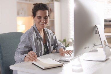 Photo of Happy woman working with computer at desk indoors. Home office