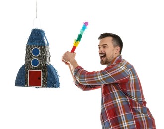 Photo of Emotional man hitting rocket shaped pinata with stick on white background