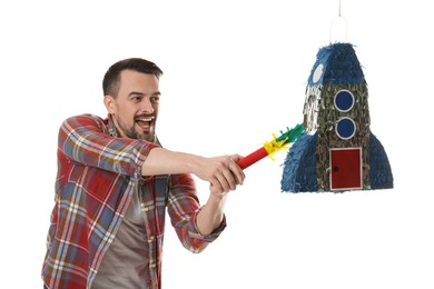 Emotional man hitting rocket shaped pinata with stick on white background