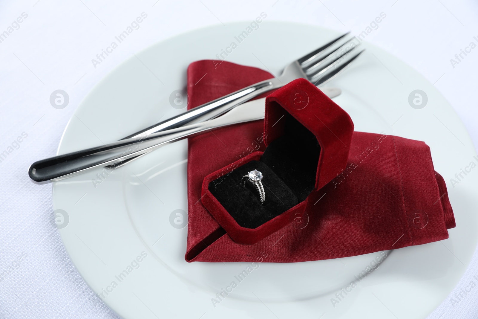 Photo of Beautiful engagement ring and setting for romantic dinner on white background, closeup