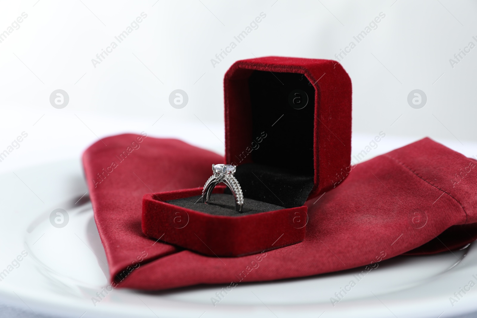 Photo of Beautiful engagement ring and setting for romantic dinner on white background, closeup