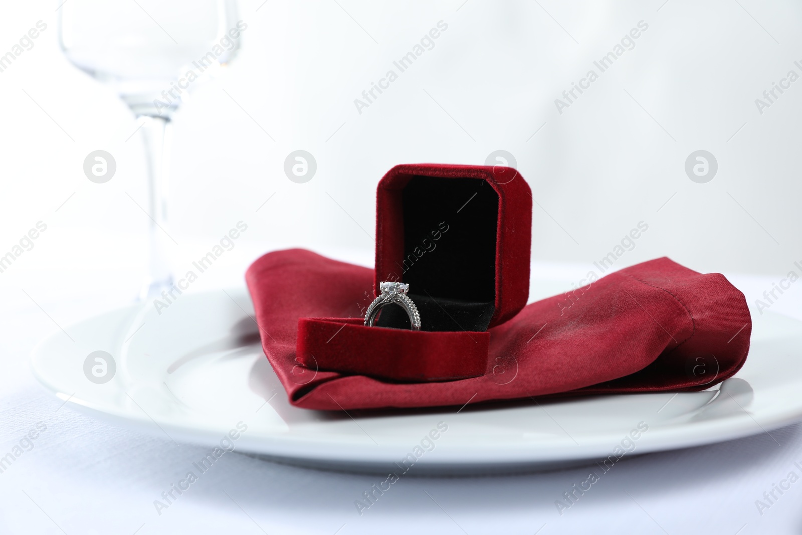 Photo of Beautiful engagement ring and setting for romantic dinner on white background, closeup