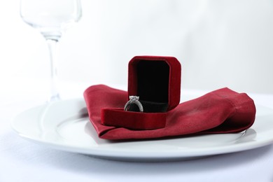 Photo of Beautiful engagement ring and setting for romantic dinner on white background, closeup