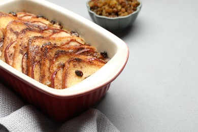 Photo of Delicious bread pudding in baking dish on light gray table, closeup. Space for text