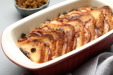 Photo of Delicious bread pudding in baking dish on light gray table, closeup