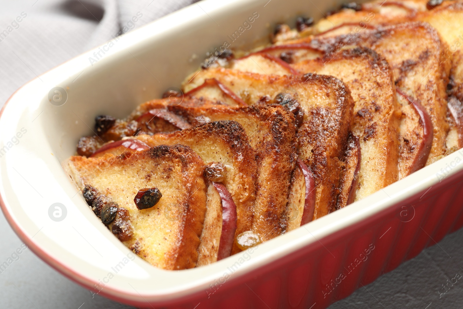 Photo of Delicious bread pudding in baking dish on light table, closeup