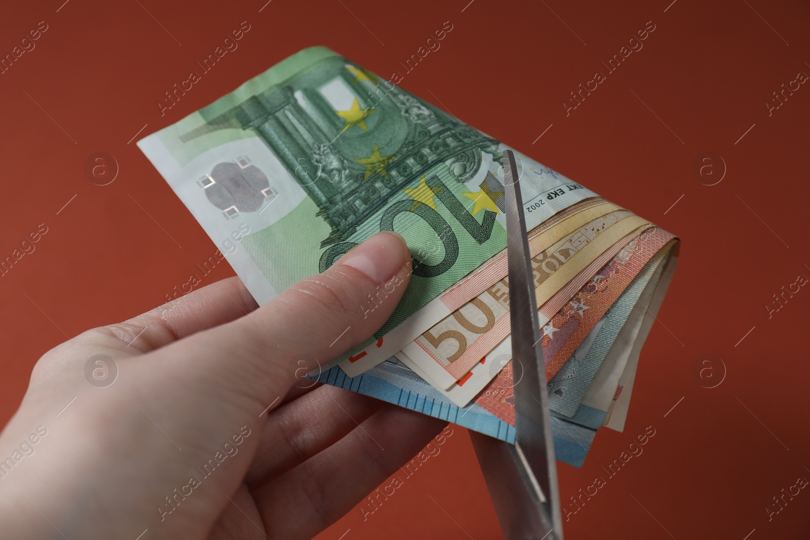 Photo of Woman cutting euro banknotes on brown background, closeup