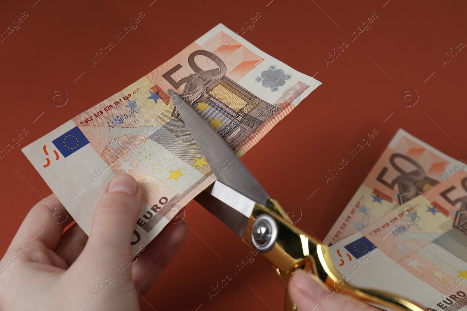 Photo of Woman cutting euro banknotes on brown background, closeup