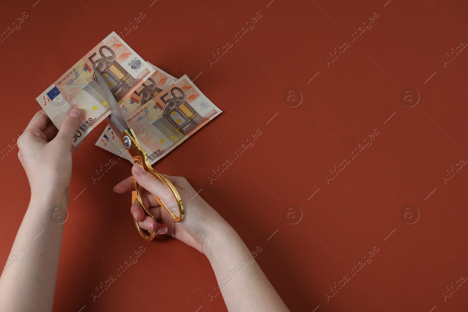 Photo of Woman cutting euro banknotes on brown background, top view. Space for text