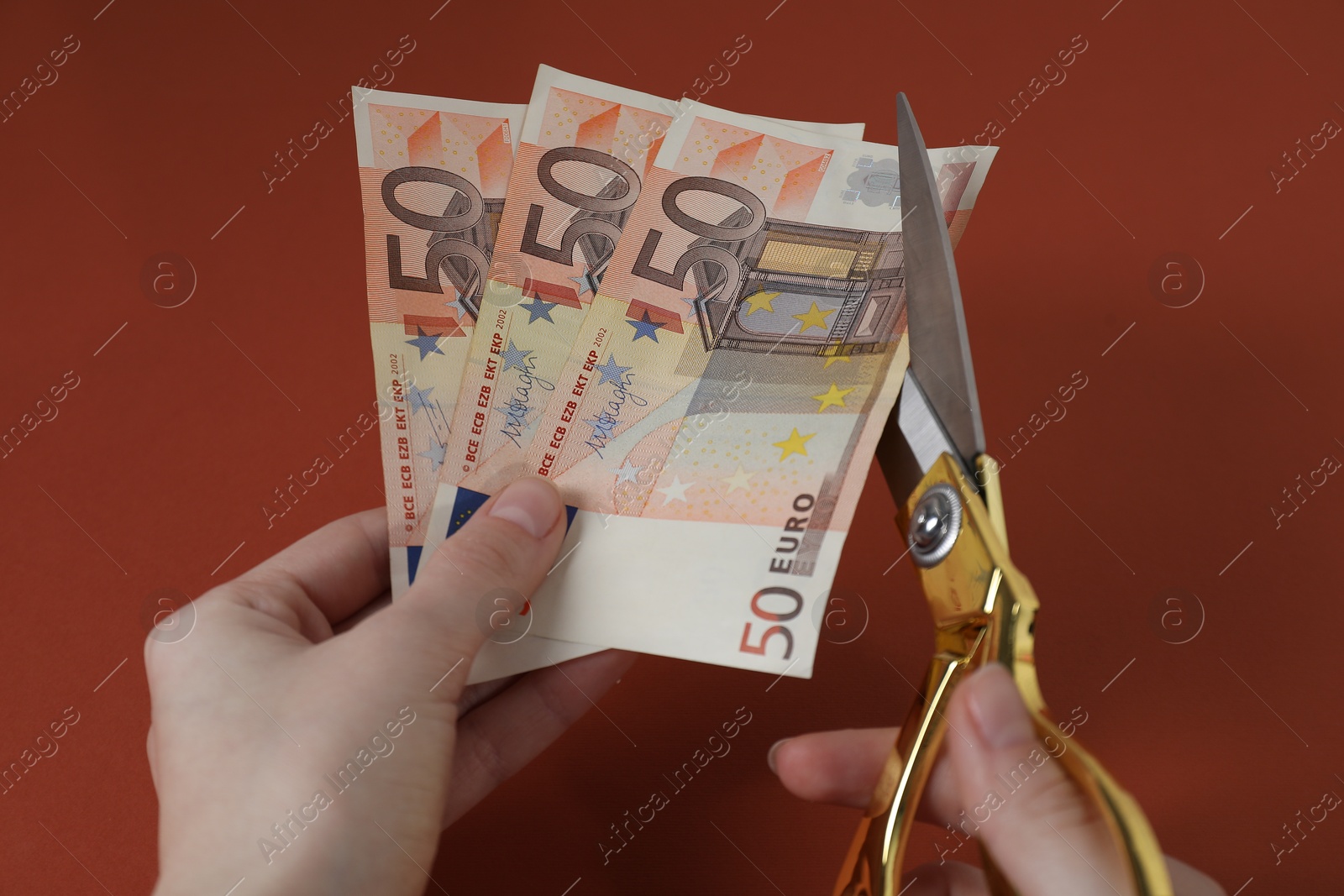 Photo of Woman cutting euro banknotes on brown background, closeup