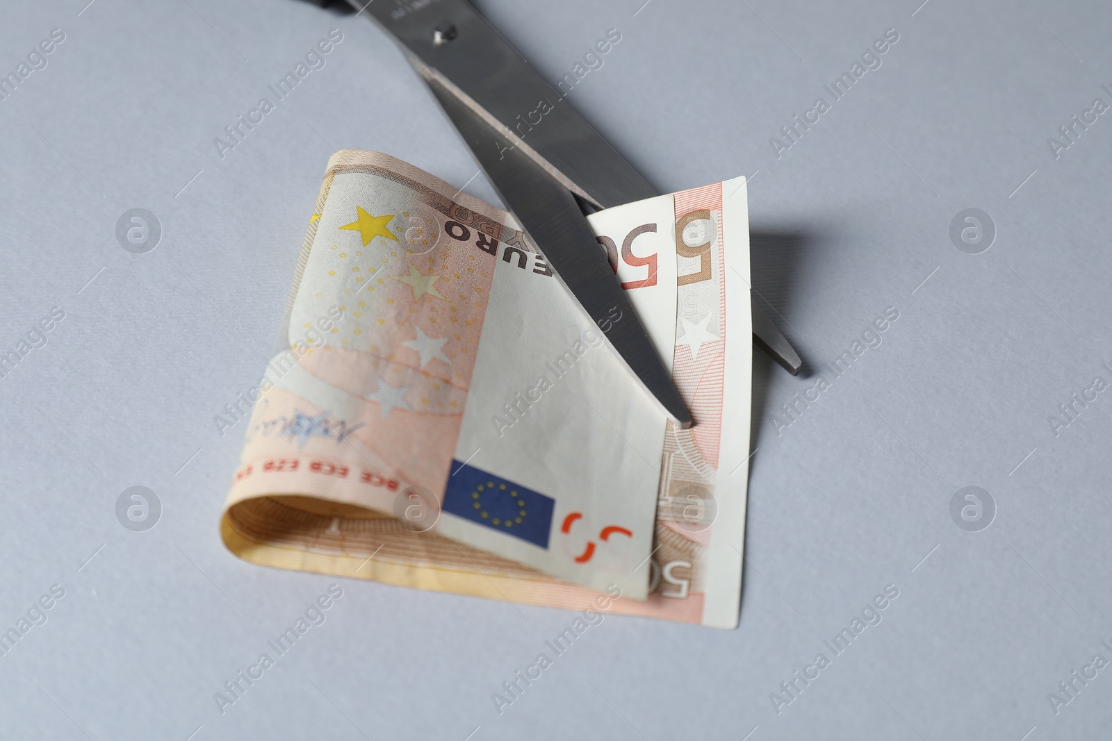 Photo of Scissors with euro banknote on gray background, closeup