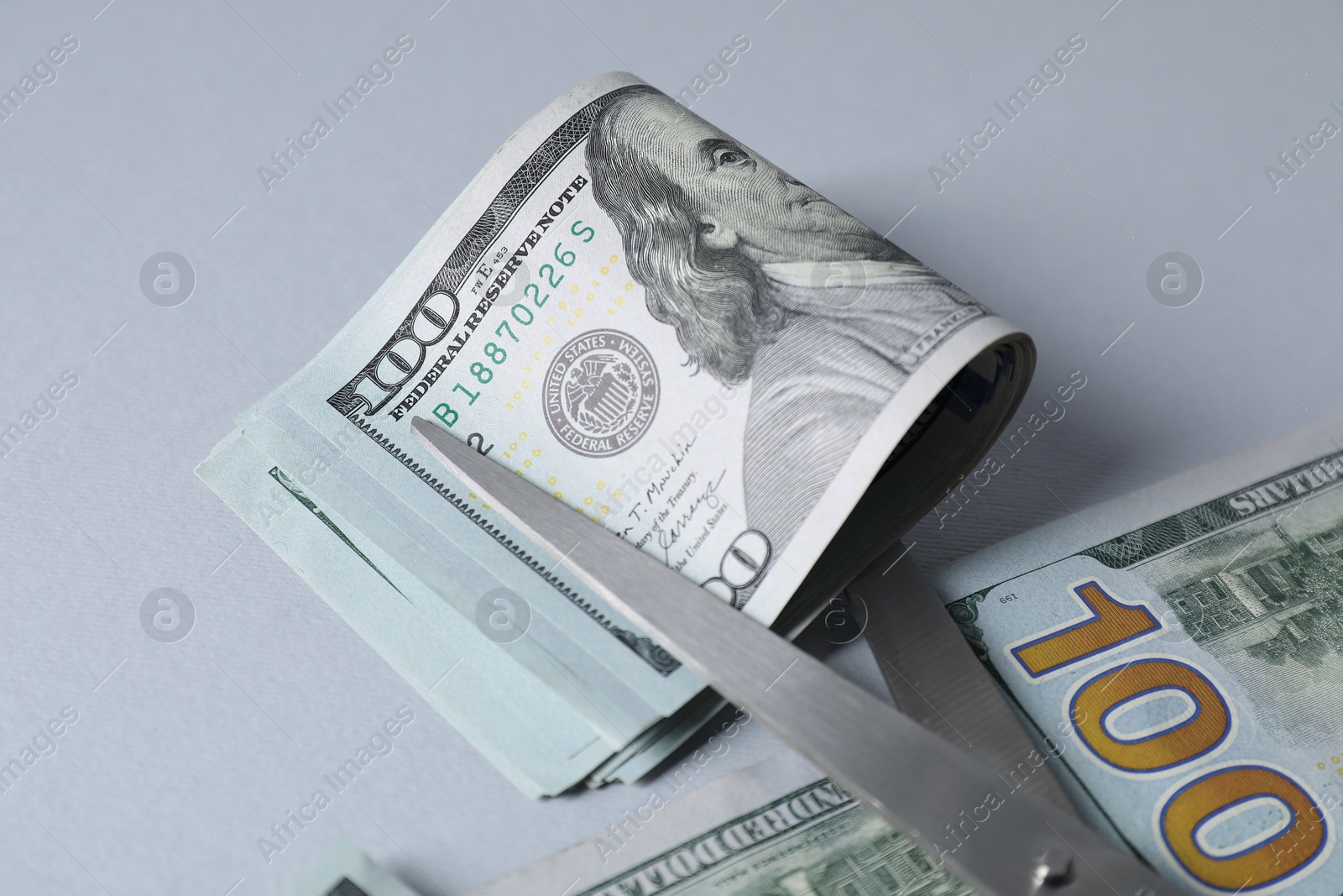 Photo of Dollar banknotes and scissors on gray background, closeup