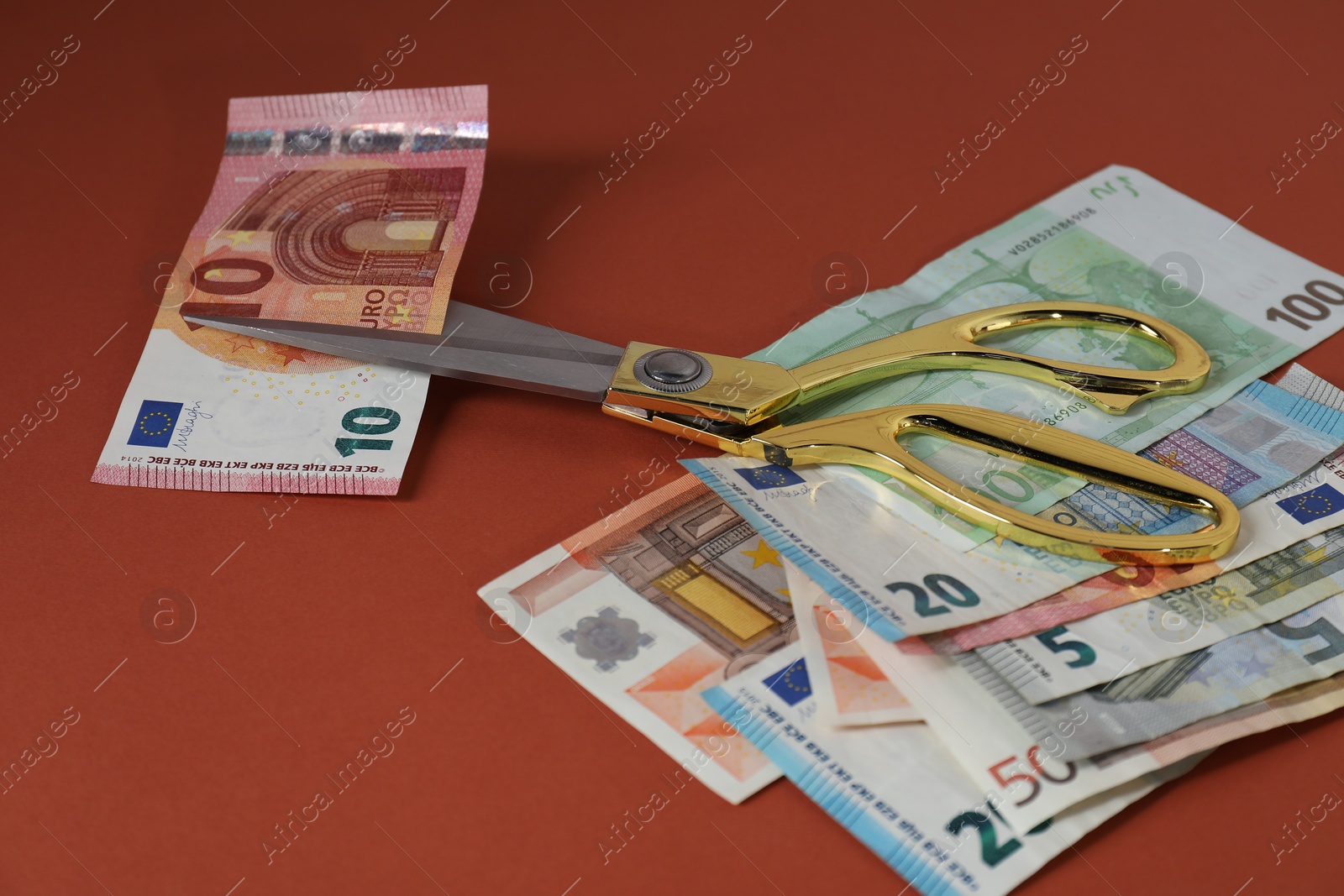 Photo of Euro banknotes and scissors on brown background, closeup