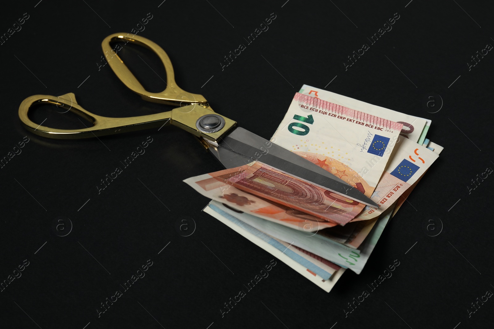 Photo of Euro banknotes and scissors on black background