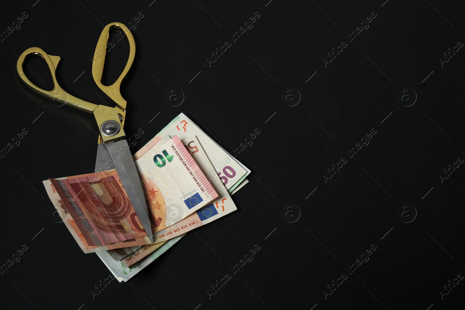 Photo of Euro banknotes and scissors on black background, space for text