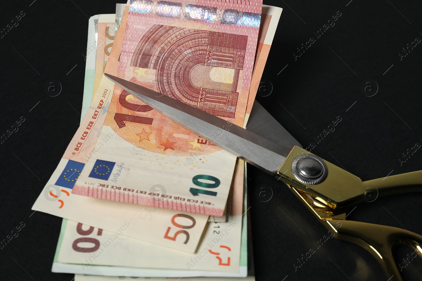 Photo of Euro banknotes and scissors on black background, closeup