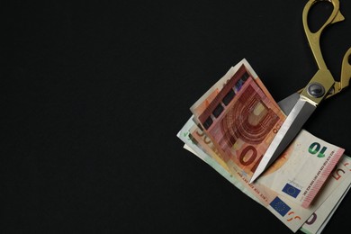 Photo of Euro banknotes and scissors on black background, space for text