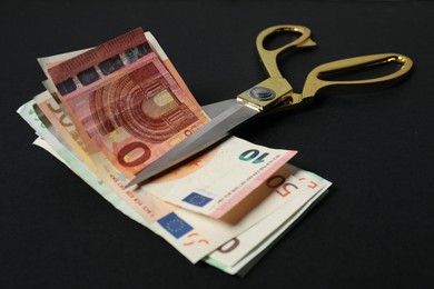 Photo of Euro banknotes and scissors on black background, closeup